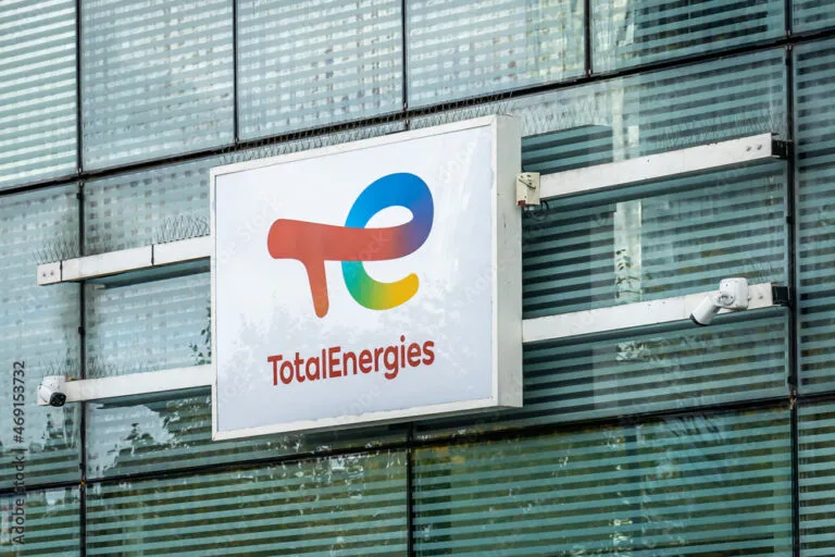 TotalEnergies logo sign mounted on a modern glass building façade.