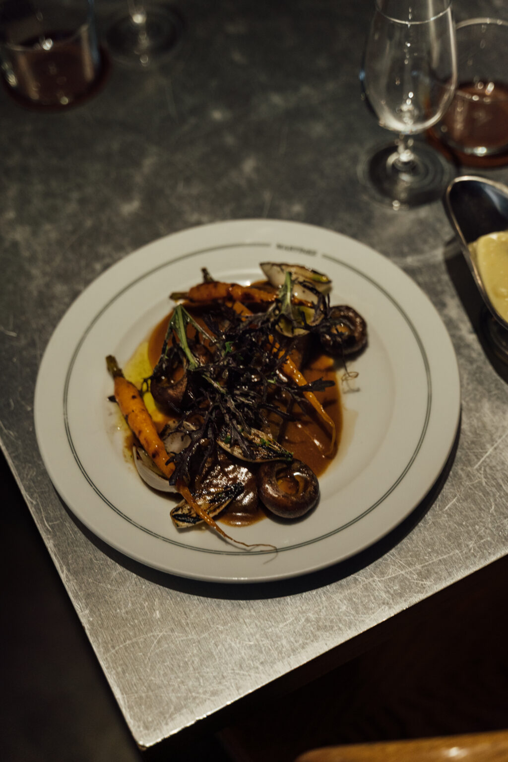 DSC00163 - Petróleo y Energía Plate with a brown sauced vegetable dish topped with seaweed garnish, on a white plate.