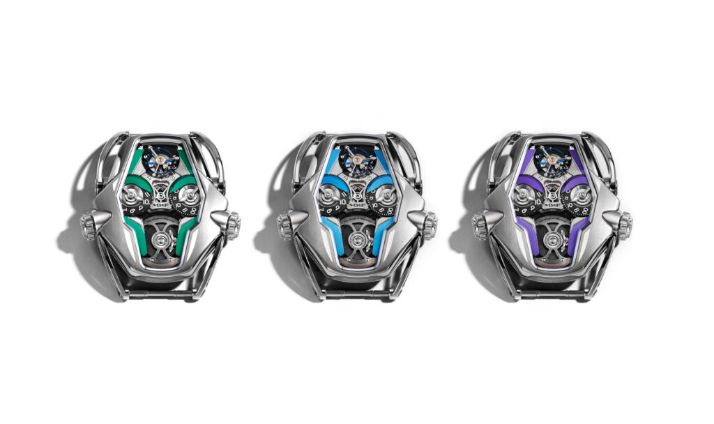 MBandF_HM12_Trio_Case_Lres - Petróleo y Energía Three futuristic wristwatches aligned in a row, each with a colorful exposed mechanism (green, blue, and purple accents) on a silver case.