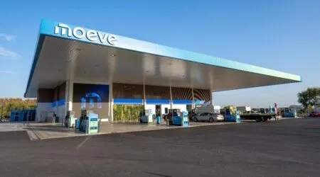 Gas station under a large blue canopy with moeve sign; cars fueling at pumps near the forecourt.