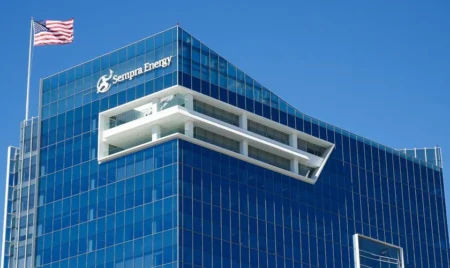 Blue glass corporate office building with Sempra Energy logo and an American flag on a clear day.