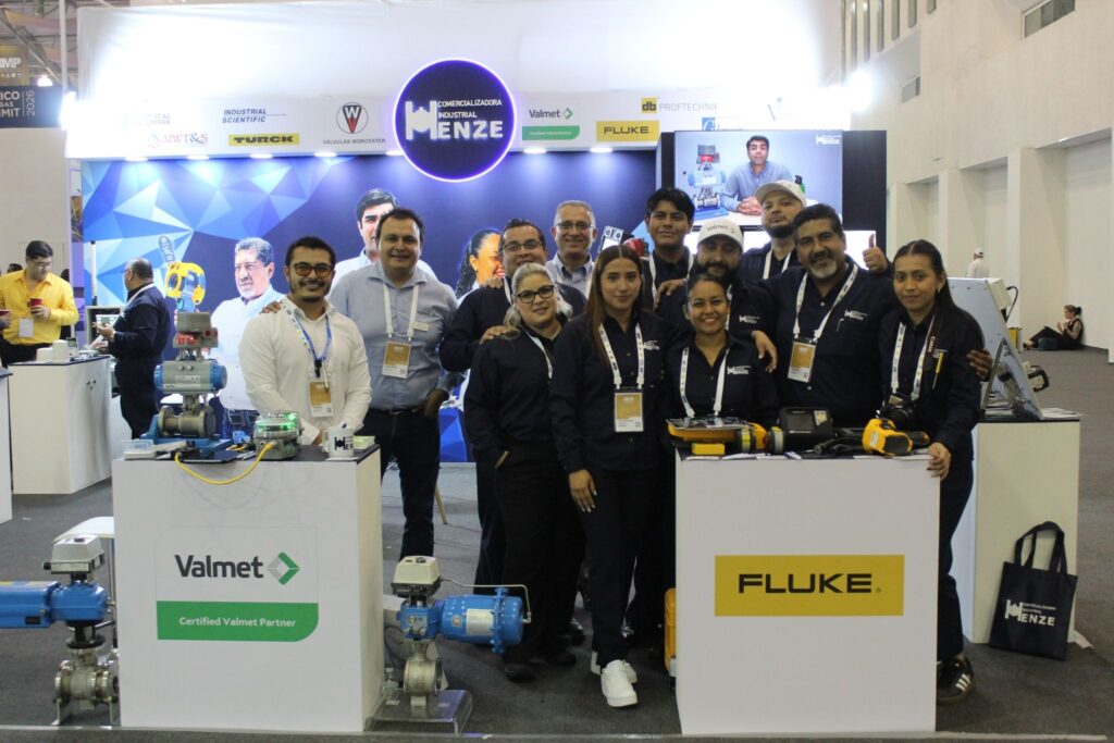 image - Petróleo y Energía Group of people posing at a trade show booth with Valmet and Fluke branding and industrial equipment on display.