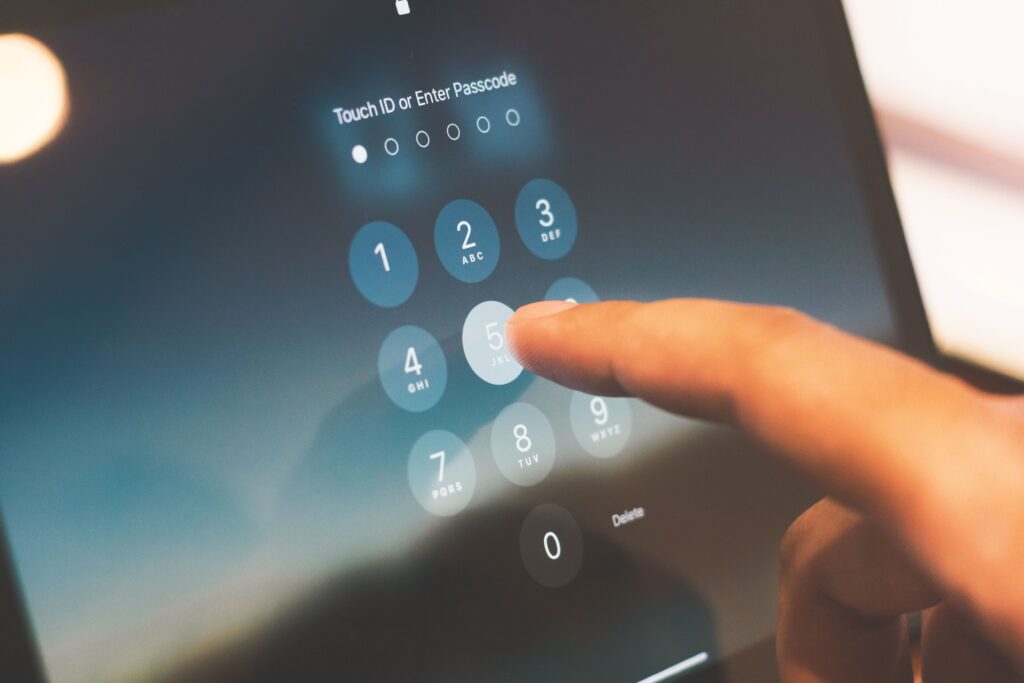 pexels-indraprojectsofficial-27742642 - Petróleo y Energía Finger tapping a blue circular on-screen keypad to enter a passcode on a touchscreen lock screen:'Touch ID or Enter Passcode' prompt visible.